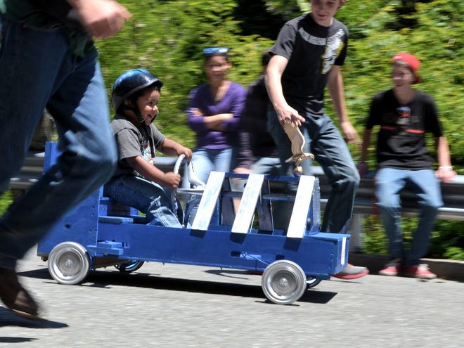 Flanked by protective bodies, little Thomas Crago VIII of Rogue River, Oregon tries out his steel wheels on the course at the Dunsmuir Dogwood Daze Soapbox Derby Saturday, May 26, 2012.