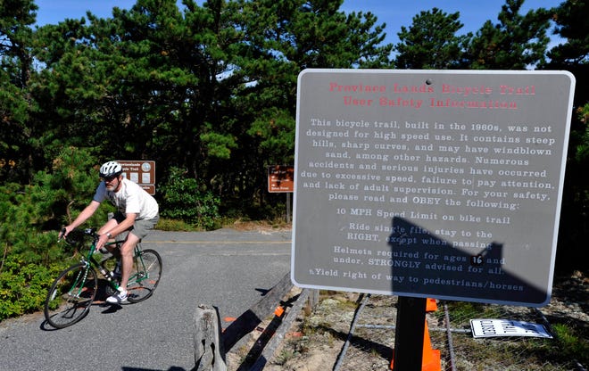 File - A cyclist rides past a safety warning sign along the Province Lands Bike trail in the National Seashore on September 15, 2009