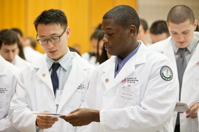 Joseph Lee (left), of Burlington Township, and Edwin Theosmy, of Neptune, reciting the student “Pledge of Commitment” during the White Coat ceremony at the University of Medicine and Dentistry of New Jersey - School of Osteopathic Medicine in Stratford, Camden County.