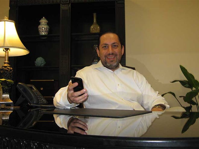 Ky Ekinci at his desk, , which is sometimes a rare occurrence, with his smart phone in hand, which is second nature to the entrepreneur and co-founder of Office Divvy in Palm Coast.