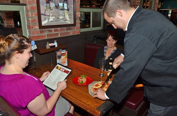 Heather East of Gananda and Jaymee Kramer of Pittsford watch as Culinary Manager Mike Wurstner cuts a Gluten Free Pizza at their table. Other Gluten items they had their table is Farro and a beer called RedBridge which is a Glueten-Free Sorghum Beer at Uno Chicago Grill in Victor.