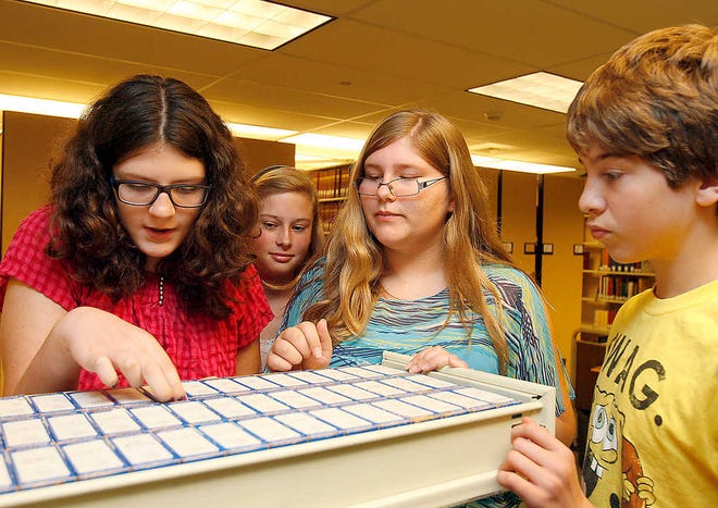 From left, Grace Hawkins, Lauren Palmer, Donna Retzlaff and Isaiah Hite find the correct year of microfilmed newspapers for the murder case they are investigating at the Topeka and Shawnee County Public Library.