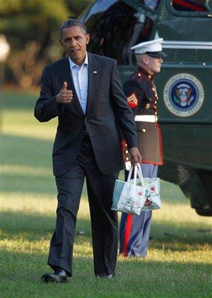 President Barack Obama gives a 'thumbs-up' as he carries bags of apples during his arrival on the South Lawn of the White House on Marine One helicopter, Saturday, Aug. 18, 2012 in Washington. Obama purchased the apples and other items in a campaign stop at Mack's Apples in Londonderry, N.H.