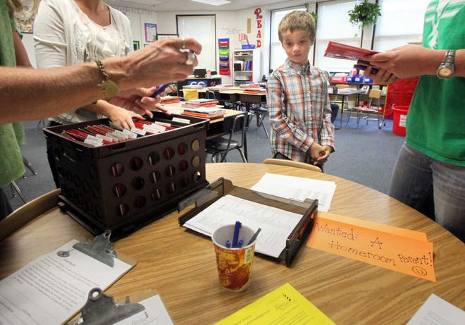 Tyler McDonald, 7, stands by as his mother, Erin McDonald, right, is handed paperwork by his new second grade teacher, Nancy Cubbedge, left, during Meet Your Teacher Day at R.B. Hunt Elementary School on Friday morning, August 17, 2012. BY DARON DEAN, daron.dean@staugustine