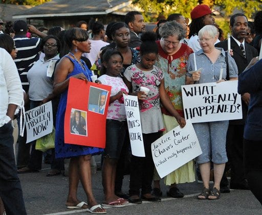 In this Aug. 6, 2012 file photo, supporters of Chavis Carter and his family, including 9-year-olds Taelor Chavis, center left, and Kimi Miller, center right, hold signs during the candlelight vigil held in honor of Carter at the First Baptist Church in Jonesboro, Ark. Carter was shot in the head while his hands were cuffed behind him in an Arkansas patrol car on July 28. An autopsy report released Monday, Aug. 20, lists Carter's death as a suicide. (AP Photo/The Jonesboro Sun, Krystin McClellan, File)