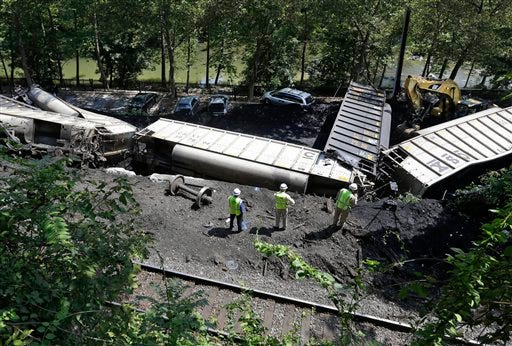 Officials inspect part of a CSX freight train that derailed alongside a parking lot overnight in Ellicott City, Md., Tuesday. Authorities say the train, hauling coal from West Virginia to Maryland, derailed and fell from a bridge near Baltimore, killing two college students who were on the tracks. Howard County officials say 21 of the train's 80 cars flipped over around midnight Monday.