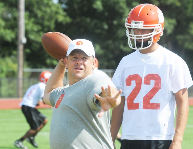Oliver Ames coach Jim Artz throws the ball as quarterback Nick Cidado looks on during the Tigers' practice in Easton on Tuesday.