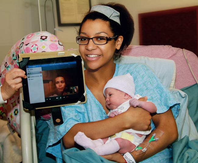 Jordyn Pritchard, Family member takes her first Family picture with her deployed husband, Spc. Branden Pritchard and their first child, Courtney Pearl Pritchard, at Womack Army Medical Center on July 30.