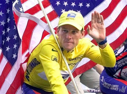 FILE - This July 23, 2000 file photo shows Tour de France winner Lance Armstrong riding down the Champs Elysees with an American flag after the 21st and final stage of the cycling race in Paris. The superstar cyclist, whose stirring victories after his comeback from cancer helped him transcend sports, chose not to pursue arbitration in the drug case brought against him by the U.S. Anti-Doping Agency. That was his last option in his bitter fight with USADA and his decision set the stage for the titles to be stripped and his name to be all but wiped from the record books of the sport he once ruled.