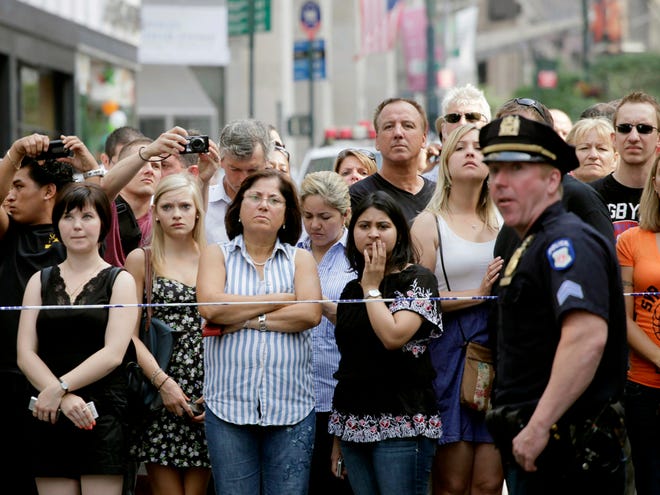 Bystanders and a police officer stand on Fifth Avenue to view the scene after a shooting outside the Empire State Building on Friday n New York. (AP)