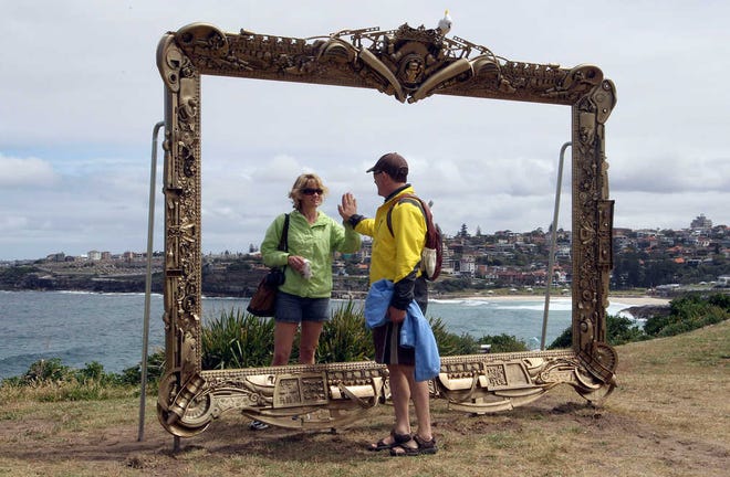 In this 2011 file photo, a couple pretends to be a mirror image of each other in Jane Gilling's sculpture, Provenance (a gift frame) at Sculptures By The Sea in Sydney, Australia.