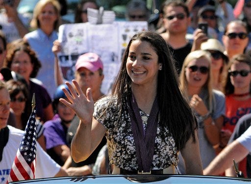Olympic gold-medal gymnast Aly Raisman waves to the crowd during a parade in her honor in Needham, Mass., on Sunday, Aug. 26, 2012. Raisman, 18, won two gold medals and a bronze at the London Summer Olympics.