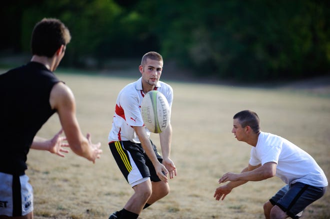 Missouri rugby player Nick Bishop passes the ball to Jeff Student while David Tresslar defends during a recent practice.