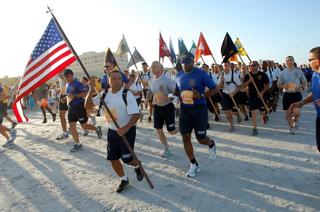 MUC (select) Jose Acosta of Navy Band Southeast proudly carries the American flag as chief petty officers (CPO) and CPO selectees from NAS Jacksonville and NS Mayport head out for the 5-mile Tijuana Flats Beach Run at Jacksonville Beach on Aug. 25.
