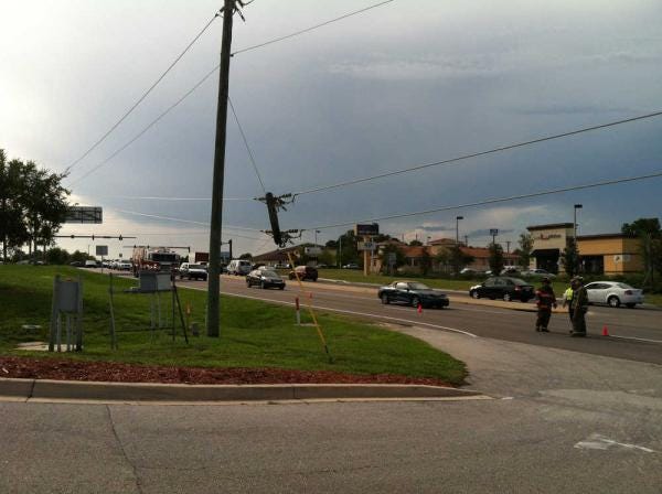 The top of a utility pole hangs from power lines in front of Carrabba's Italian Grill on State Road 312 on Thursday afternoon. The pole broke just before 5 p.m. and caused power outages to 1,700 customers, said Florida Power & Light Company spokesman Neil Nissan.