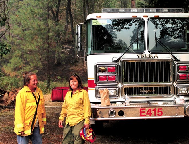 Local firefighters Barbara Geidel (left), with the Seiad Volunteer Fire Department and Helen Smith (right), with the Klamath National Forest, stand in front of a fire line that burned right up to a resident's back yard. Flames came within 100 feet of the home but no structures were damaged. Daily News Photo/John Bowman