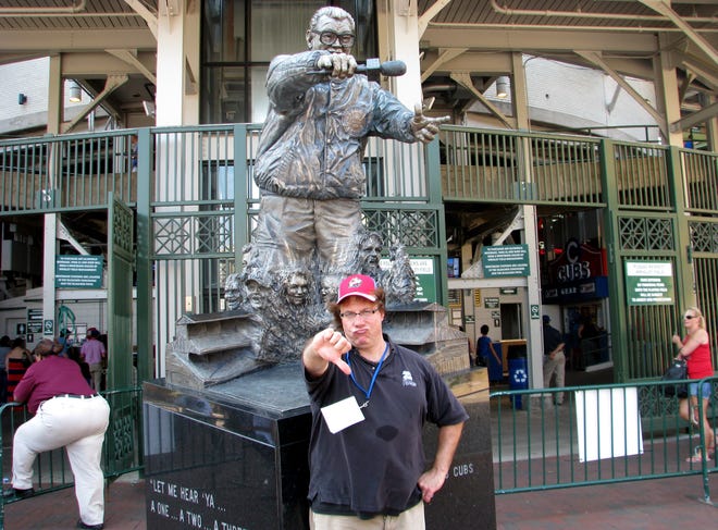 Journal Star columnist Phil Luciano stands in front of the Harry Caray statue on Thursday outside Wrigley Field in Chicago, giving the thumbs-down to his failed attempt to meet with Cubs chairman Tom Ricketts and discuss keeping the team's Class A affiliation with the Peoria Chiefs. He was able to deliver a packet of hundreds of signatures supporting the affiliation to Ricketts' office.