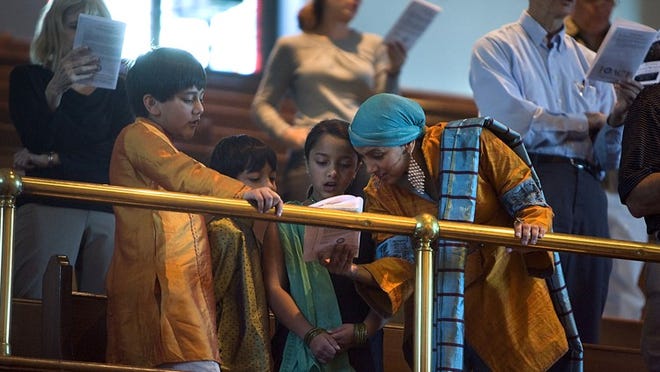 Sarah Siddiqi and her children, from left, Tibraan, 12, Ilaan, 8, and Raya, 10, sing during the 26th annual Interfaith Thanksgiving Service and Celebration at University Baptist Church on Sunday.