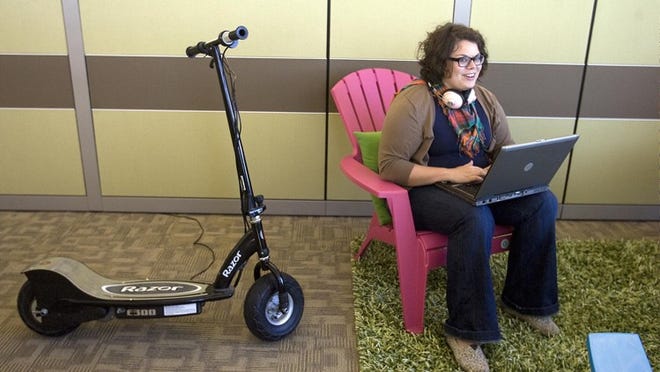 Brittany Blackmon works on her laptop in the technical support lounge. The scooter beside her is used to get to other offices at the company, which is spread over a large space and multiple floors.