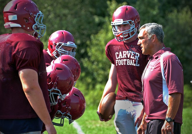 Carver High School head football coach Mike Fraccalossi huddles with his players, including starting quarterback Ryan Feeley at his side, at practice on Thursday, Aug. 30, 2012.