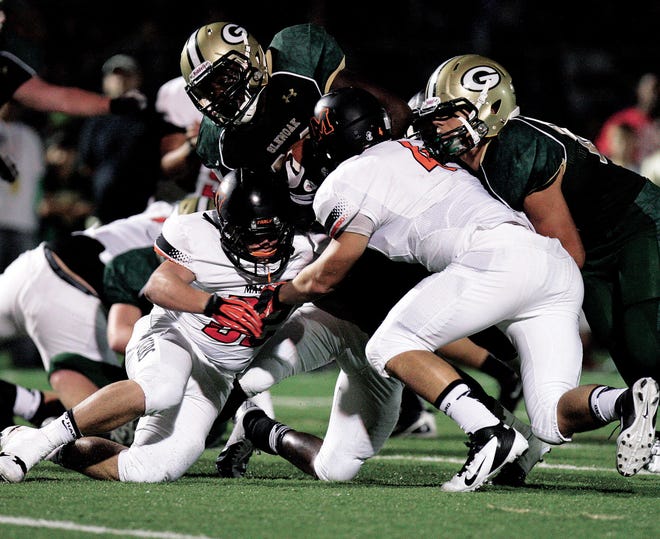 GlenOak's Justin Smith fights for yards as Massillon's Ryne Moore, left, and Danny Robinson trying to make the stop in the first half. GlenOaks Kyle Bungo is also in on the play.