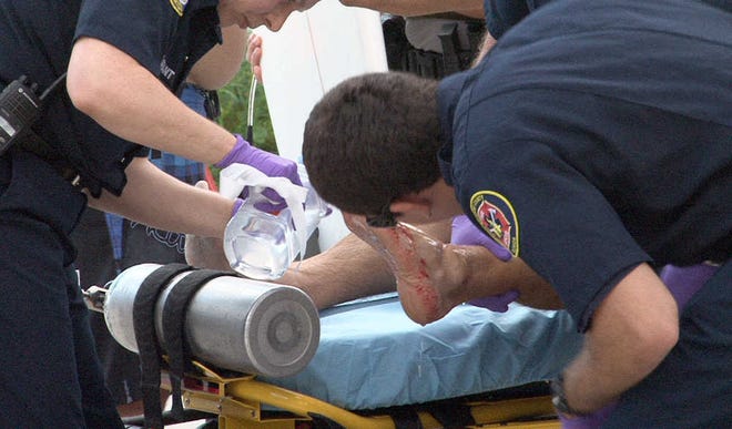 St. Johns County Fire Rescue paramedics treat a man who was bitten on the foot while surfing near A Street in St. Augustine Beach on Thursday morning, September 6, 2012. By ALAN ALSOBROOK, Special to The Record