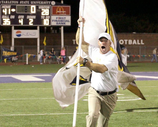 Stephenville head coach Joe Gillespie took a run with the giant Yellow Jacket flag moments after his team finished a 41-28 victory over Aledo at Tarleton Memorial Stadium Friday night.