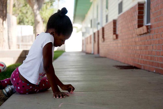 Malasiah Petty, 6, uses sidewalk chalk to draw outside her apartment in the cool weather.