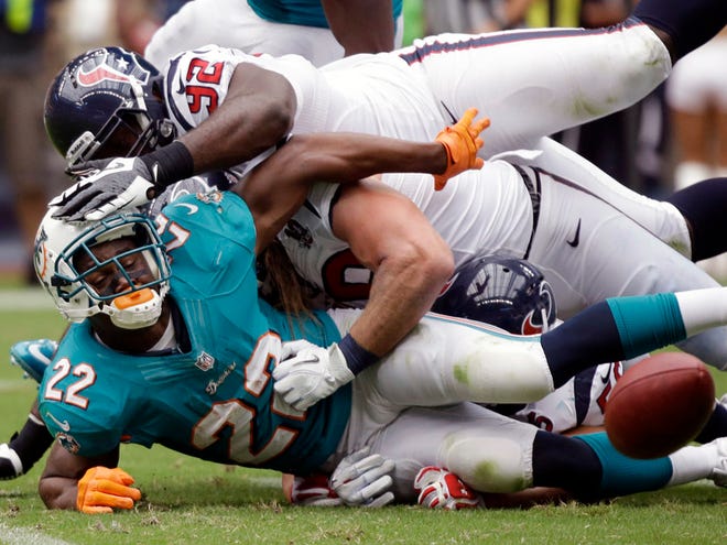 Dolphins running back Reggie Bush (22) fumbles the ball after being tackled by the Texans' Earl Mitchell (92) and Brooks Reed, center, in the first quarter Sunday in Houston.