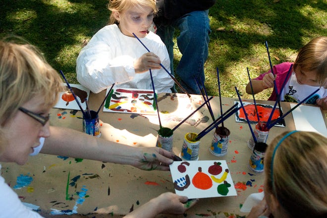Kyleigh Hartley of Galesburg, 8, top, paints a bowl of fruit at a table for children to explore and create painting projects Saturday in Standish Park during Art in the Park.
