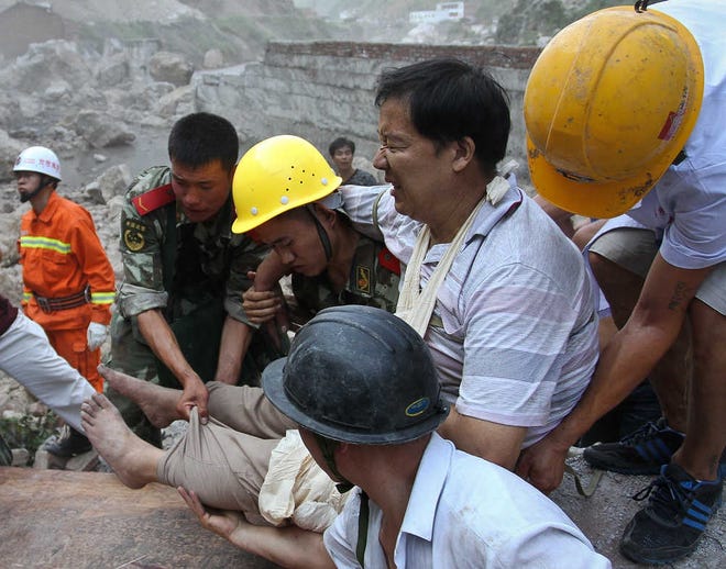 Chinese paramilitary policemen and a citizen use a wooden platform to evacuate an injured man Saturday after twin earthquakes Friday.  Rescue workers cleared roads Saturday so they could search for survivors and rush aid to a remote mountainous area of southwestern China after twin earthquakes killed at least 80 people. (AP Photo) CHINA OUT