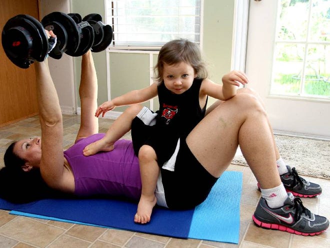 Michelle Rutkowski, 39, works out as her 18-month-old daughter Caylyn joins in on occasion at her home in Daytona Beach. When it comes to juggling work and family obligations, parents have to find creative ways to take time out for themselves, says Rutkowski, who is a home fitness coach.