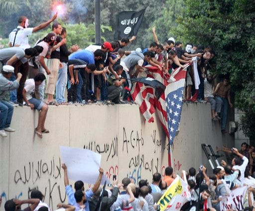 Protesters destroy an American flag pulled down from the U.S. embassy in Cairo, Egypt, Tuesday. Egyptian protesters, largely ultra conservative Islamists, have climbed the walls of the U.S. embassy in Cairo, went into the courtyard and brought down the flag, replacing it with a black flag with Islamic inscription, in protest of a film deemed offensive of Islam.