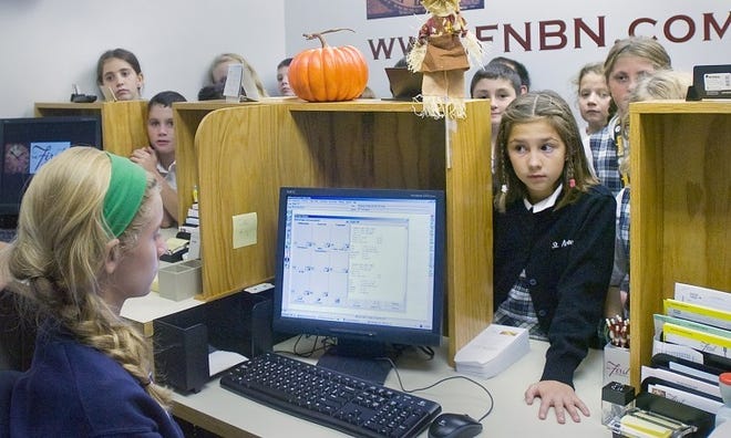 Fifth-grader Alexa Klauder (right) and her classmates check out the new First National Bank and Trust Co. of Newtown in-school banking branch at St. Andrew's School in Newtown when it opened last year. The bank is staffed by students and open two days a week for deposits and withdrawals. Bucks County Courier Times file photo.
