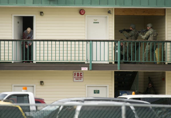 Police close in on a suspect after a shootout at a hotel in Anchorage, Alaska. A bullet grazed an officer's back during the exchange, and the shooter - one of three people in the hotel room - also might have been struck before he surrendered, according to Anchorage police. Neither had life-threatening injuries, police said. Police were investigating burglaries nearby, but what led to yesterday's confrontation was unclear.