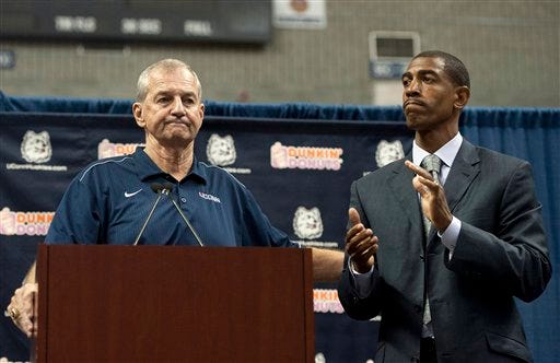 Connecticut head coach Jim Calhoun, left, reaches out to as Kevin Ollie, right, during a news conference announcing Calhoun's retirement, Thursday, Sept. 13, 2012, in Storrs, Conn. Ollie, an assistant coach under Calhoun, will succeed him.