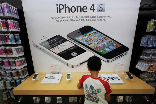 A boy checks an iPhone at an Apple booth at an electronic store in Tokyo. Millions of people will likely buy new iPhones later this month.