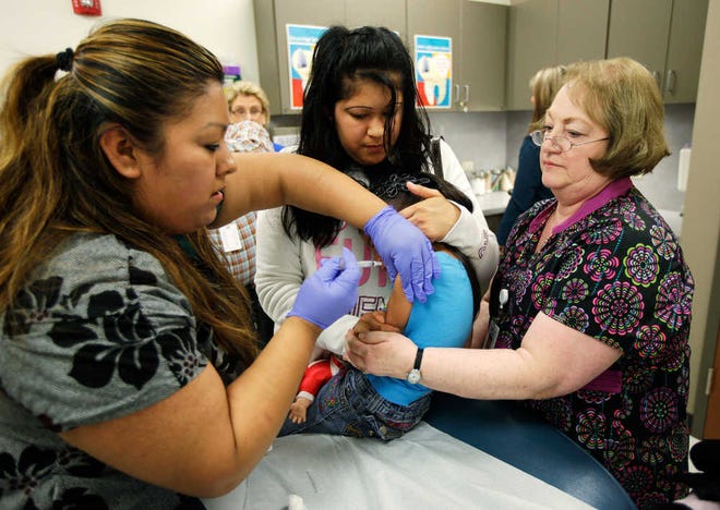 Nurses Fatima Guillen, left, and Fran Wendt, right, give Kimberly Magdeleno, 4, a Tdap whooping cough booster shot, as she is held by her mother, Claudia Solorio, Thursday, May 3, 2012, at a health clinic in Tacoma, Wash. Washington Gov. Chris Gregoire opened up an emergency fund Thursday to help contain a whooping cough epidemic in the state as officials urged residents to get vaccinated. (AP Photo/Ted S. Warren)