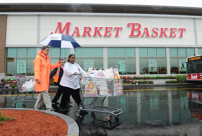Jeannette Thompson of Mattapan is escorted to her car by Danny Fernandes, left, and Rudy Sanchez during the grand opening of the Market Basket in Brockton on Tuesday, May 22, 2012.