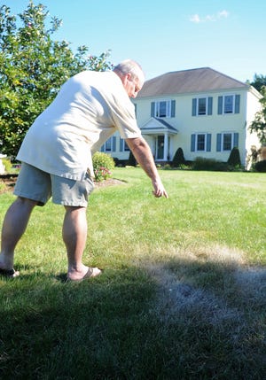 Bob Lowder points out a burned patch of grass in his front yard on Grange Court in Bridgewater where the state police bomb squad diffused a homemade explosive device, a soda bottle full of a combination of chemicals, and found remnants of others that had exploded early on Sunday morning, September 16, 2012.