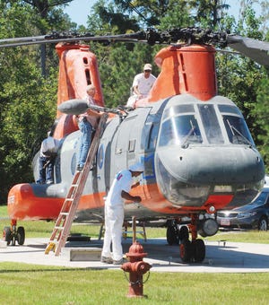 Havelock Commissioner Jim Stuart, on ladder, watches as a crew from McGowan Painting Contractors begins work on the job to paint an HH-46 helicopter at the Havelock Tourist and Event Center. The crew is also painting the RF-48 jet.