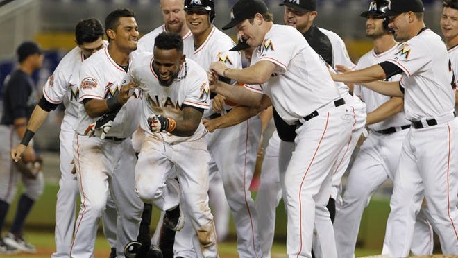Teammates congratulate Miami Marlins' Jose Reyes, foreground, after Reyes hit a two-out RBI single to defeat the Atlanta Braves 4-3 during the 10th inning of a baseball game, Tuesday, Sept. 18, 2012, in Miami. (AP Photo/Wilfredo Lee)