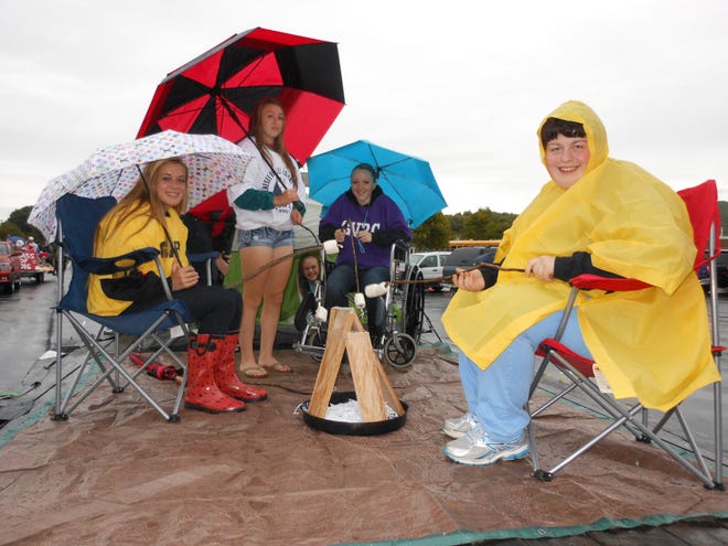 Don't rain on my parade. Last Friday's Homecoming parade almost didn't happen due to downpours. But high schoolers braved the soggy atmosphere as rains receded. From left, Breden Gibson, Katie Schledorn, Hannah Farrell, Logan Bindley (peeking out of the tent) and Ashlee Acomb get ready to go on the Junior Class' float honoring Genesee Valley Rotary Camp