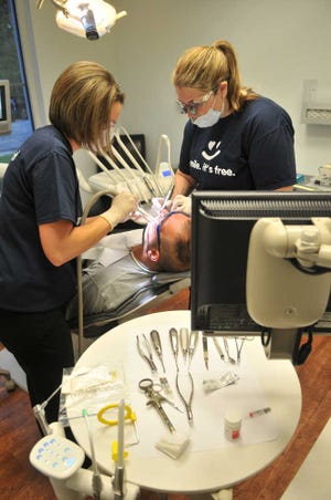 Steve Bisson/Savannah Morning News Dr. Diana Cicchiello Smith, right, a volunteer from Brunswick, extracts a tooth from Terry Spoon with the help of dental assistant Ashley Stewart.