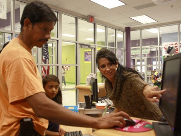 Tracy Holt, receptionist at Town Creek Elementary, helps Belen Vera check-in his daughter Esmeralda during FridayÕs school day. Holt is at the frontline of customer service in Brunswick County Schools, and an upcoming audit will help assess the district's ability to meet the needs of its parents.