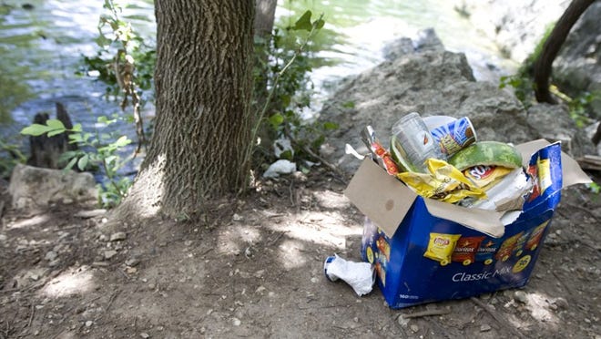 A box that held snack packs is abandoned on the bank near Twin Falls in mid-June, filled with empty Fritos bags, drink containers and watermelon rinds.
