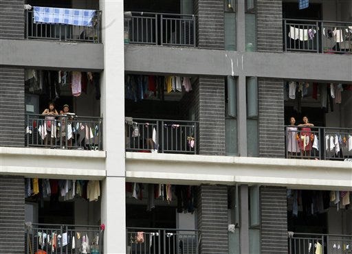In this Wednesday, May 26, 2010, file photo, employees stand on the balconies of a residential house at the Foxconn complex in Shenzhen, China. Foxconn, the company that makes Apple's iPhones suspended production at a factory in China on Monday, Sept. 24, 2012, after a brawl by as many as 2,000 employees at a dormitory injured 40 people. The fight, the cause of which was under investigation, erupted Sunday night at a privately managed dormitory near a Foxconn Technology Group factory in the northern city of Taiyuan, the company and Chinese police said. (AP Photo/Kin Cheung, File)