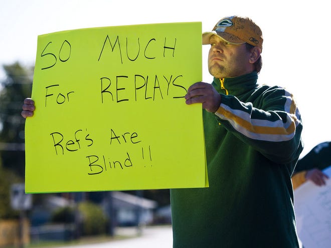Green Bay Packers fan Mike LePak holds a sign Tuesday on Lombardi Avenue in Green Bay, Wisc., in protest of a controversial call in the Packers' 14-12 loss to the Seattle Seahawks on Monday night in Seattle.