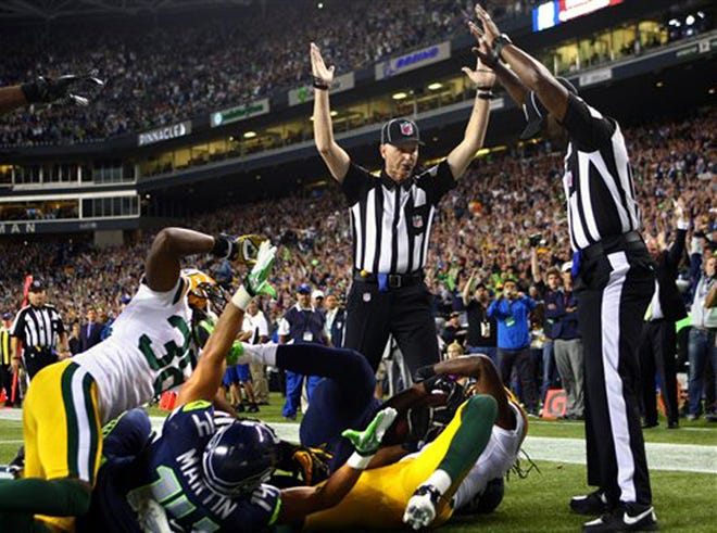 Officials signal after Seattle Seahawks wide receiver Golden Tate pulled in a last-second pass for a touchdown from quarterback Russell Wilson to defeat the Green Bay Packers 14-12 in an NFL football game, Monday, Sept. 24, 2012, in Seattle. The touchdown call stood after review.