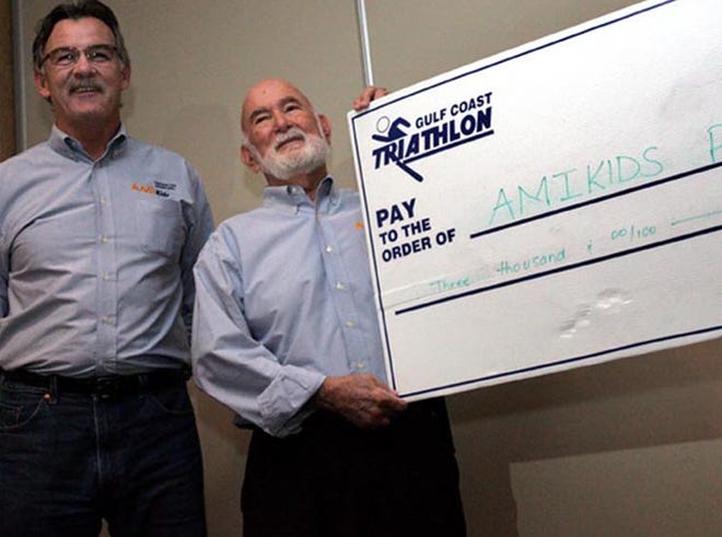 Panama City Marine Institute Executive Director Mark Carroll and institute board member Norm Gulkis pose with an oversized $3,000 check from the Gulf Coast Triathlon board at the Boardwalk Beach Resort in Panama City Beach on Tuesday.